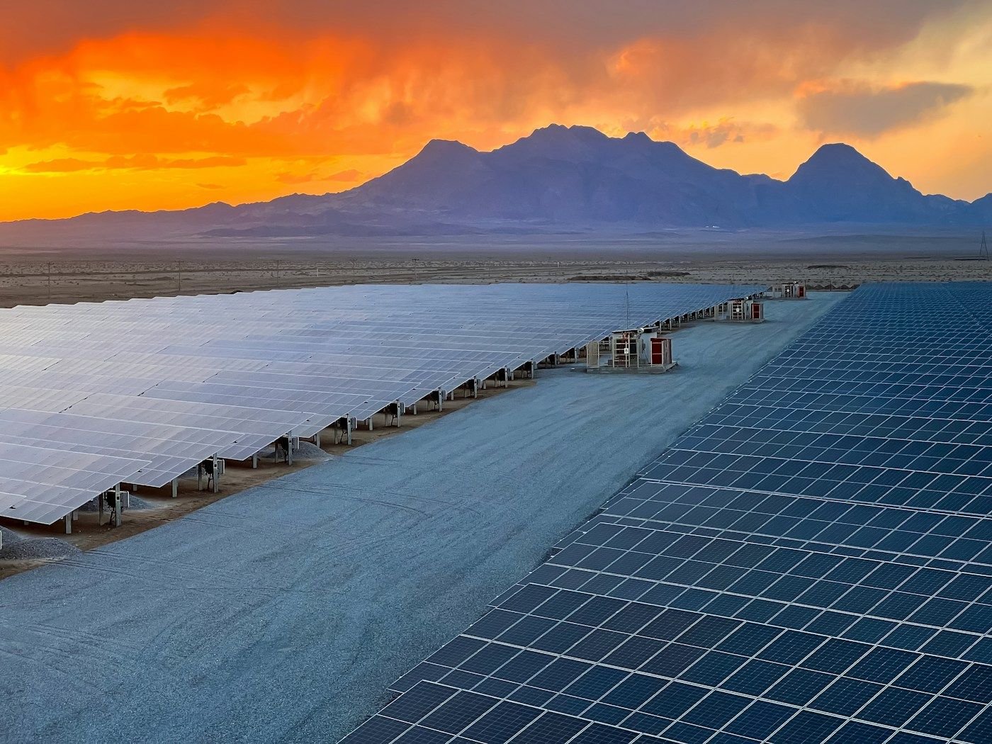 Solar farm below mountains at sunset